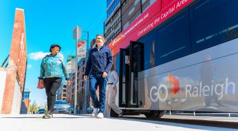 Two riders walking away from the bus in Downtown Raleigh